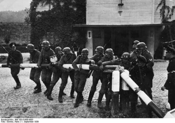 Schwarzweiß-Foto von Hans Sönnke. Es zeigt deutsche Soldaten, die den Abriss eines polnischen Schlagbaums nachstellen.