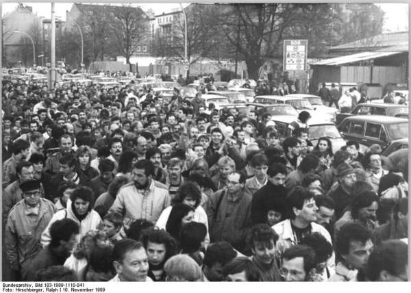 Schwarzweiß Fotografie der Menschenmasse (auch Autos), die sich am 10. November 1989 am Grenzübergang an der Invalidenstraße in Berlin drängen