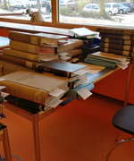 Foto eines mit Büchern und Akten voll gestapelten Schreibtisches im Lesesaal Hamburg.