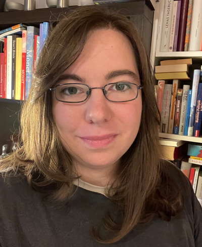 Foto einer Frau mit Brille vor einem Bücherregal